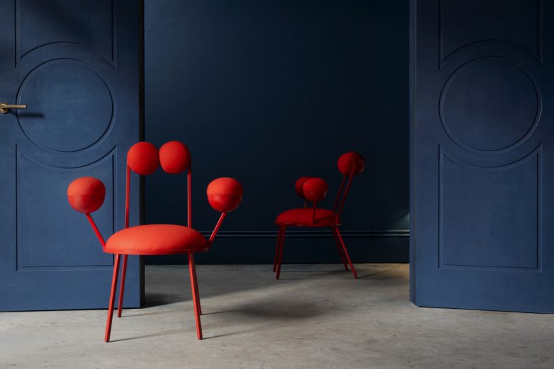 two red geometric armchairs in front of a dark wall