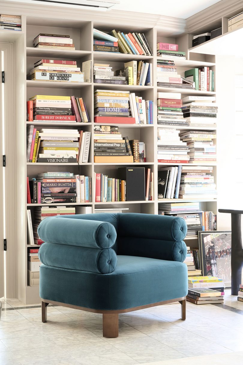 turquoise chair in front of large bookcase