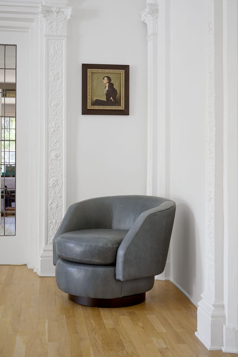 grey swivel chair in front of white walls with artwork