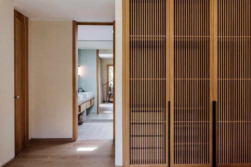 view into large modern bathroom with wooden closets