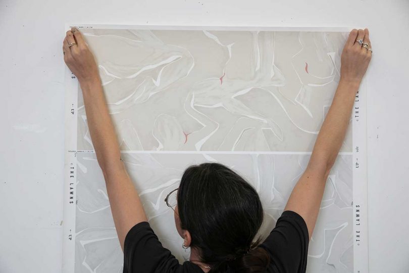 artist reviewing wallpaper colorways on the wall