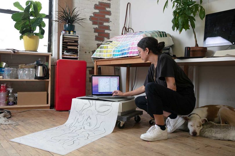 artist on floor scanning large drawing onto computer in studio