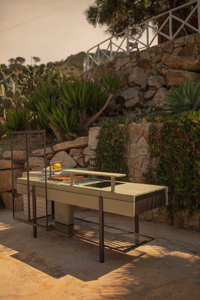 open space kitchen outdoors against rocky wall with vegetation