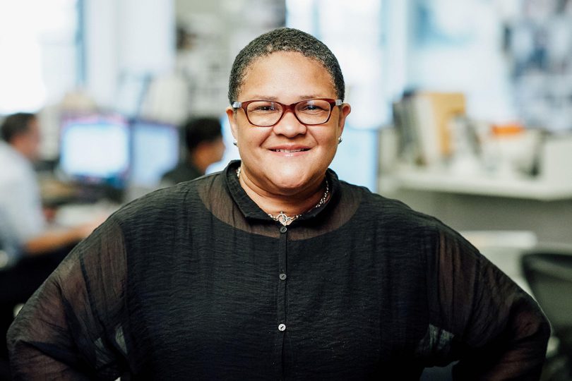 brown skinned woman with short hair and glasses wearing black