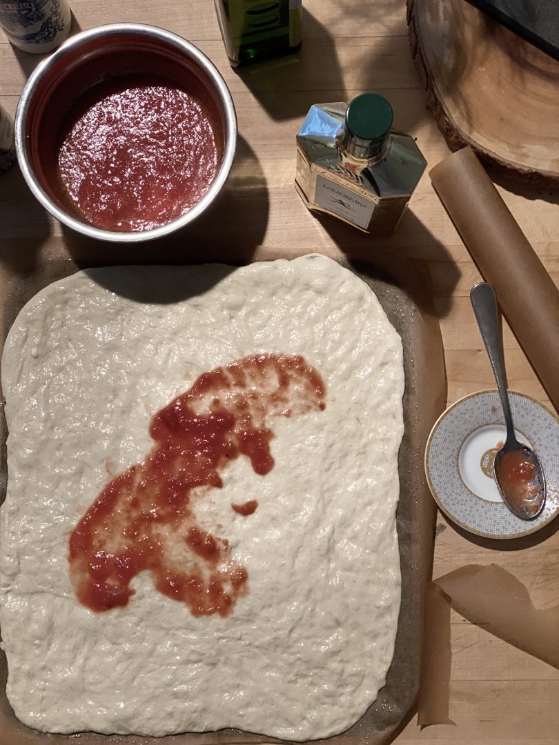 unbaked pizza dough and sauce sitting on counter