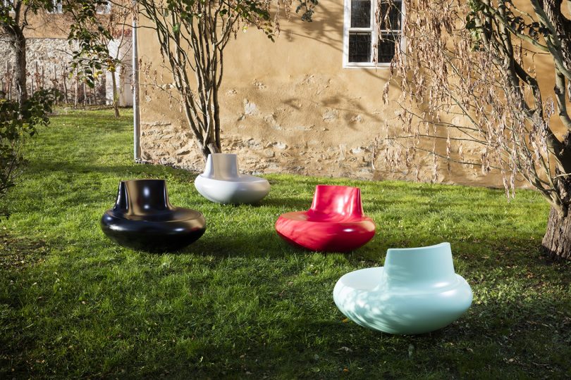 black, white, red, and light blue rounded chairs scattered around a grassy space