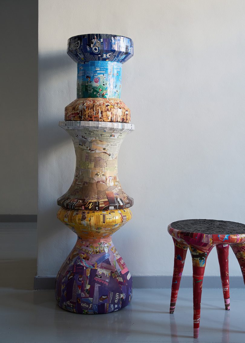 three stacked collaged stools and one lone stool in interior space