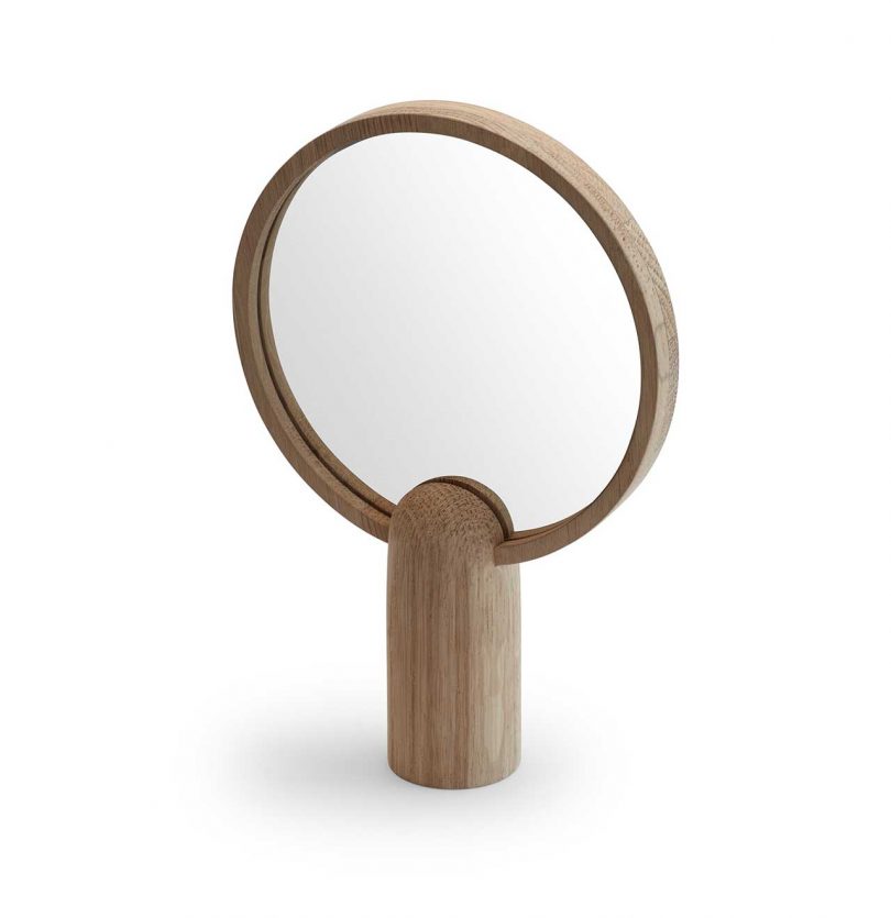 wood framed round mirror atop a wood base