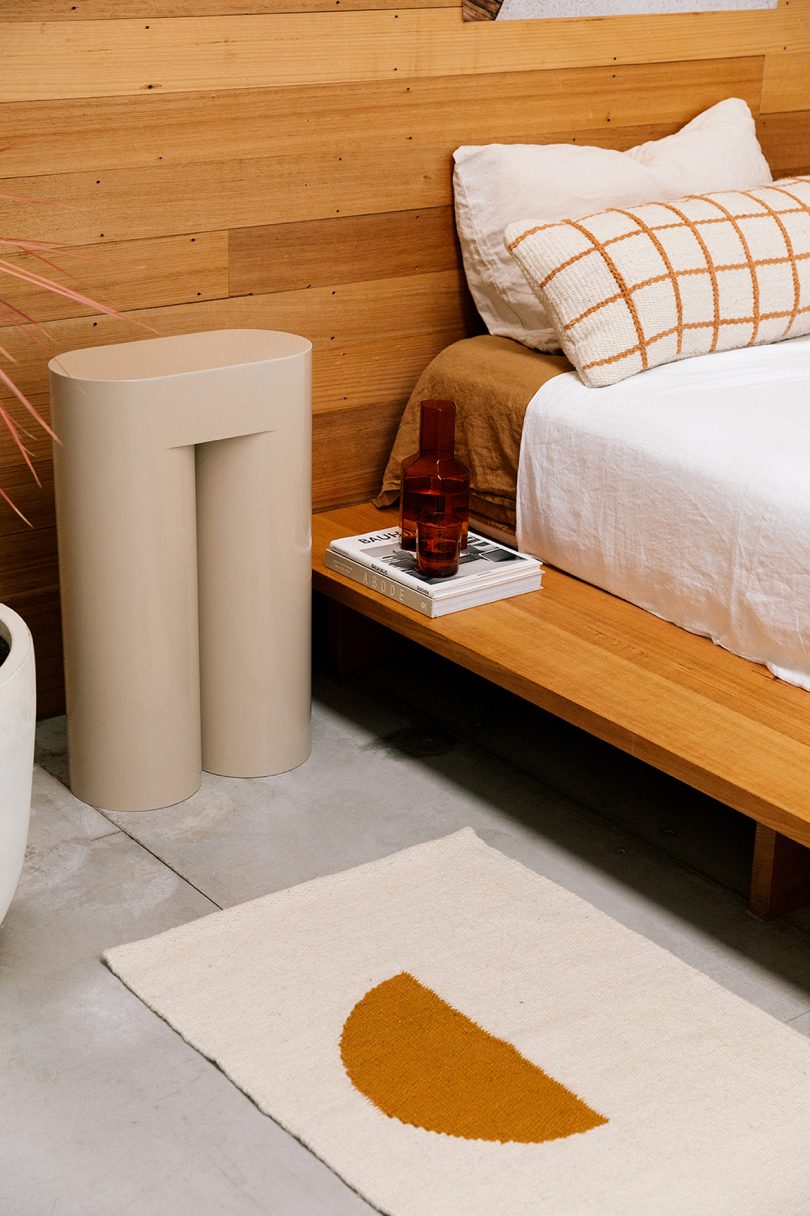 bedside with sculptural table and small woven rug