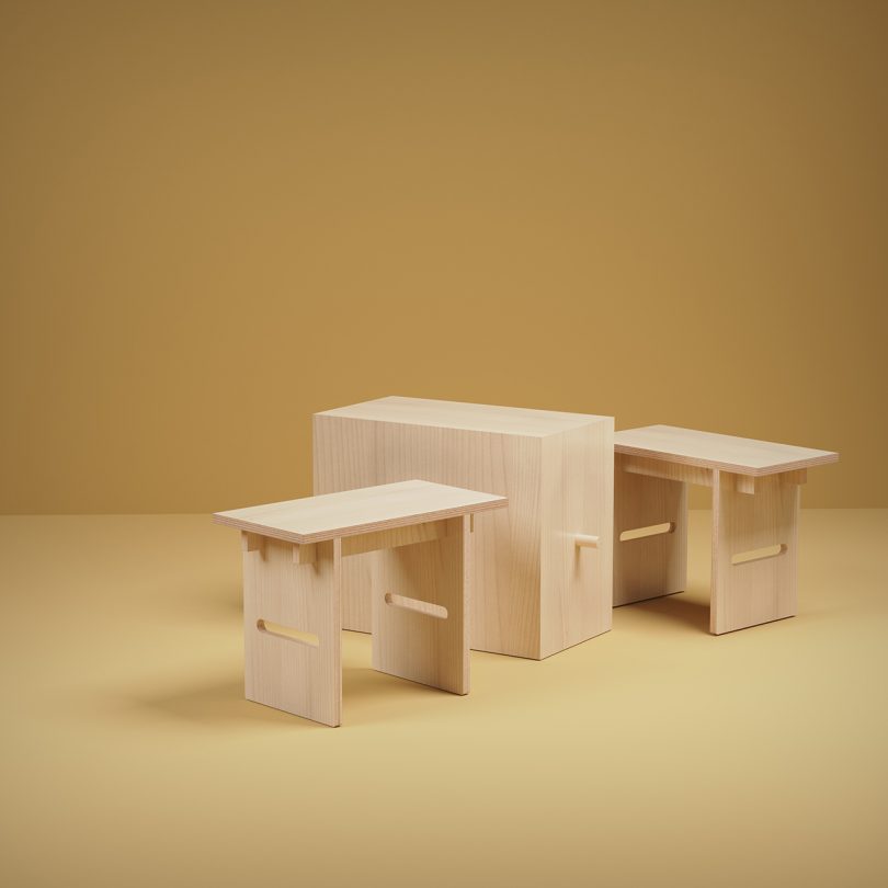 unfinished wood table and two stools on golden yellow background