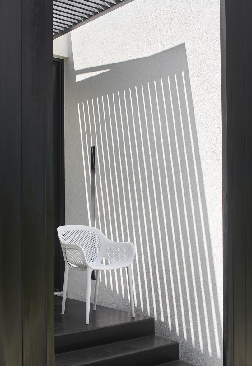 white outdoor armchair next to white slatted architectural feature