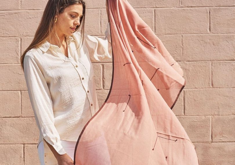 Woman holding the Clay Mist Scarf by Studio Variously letting it drape in the wind 