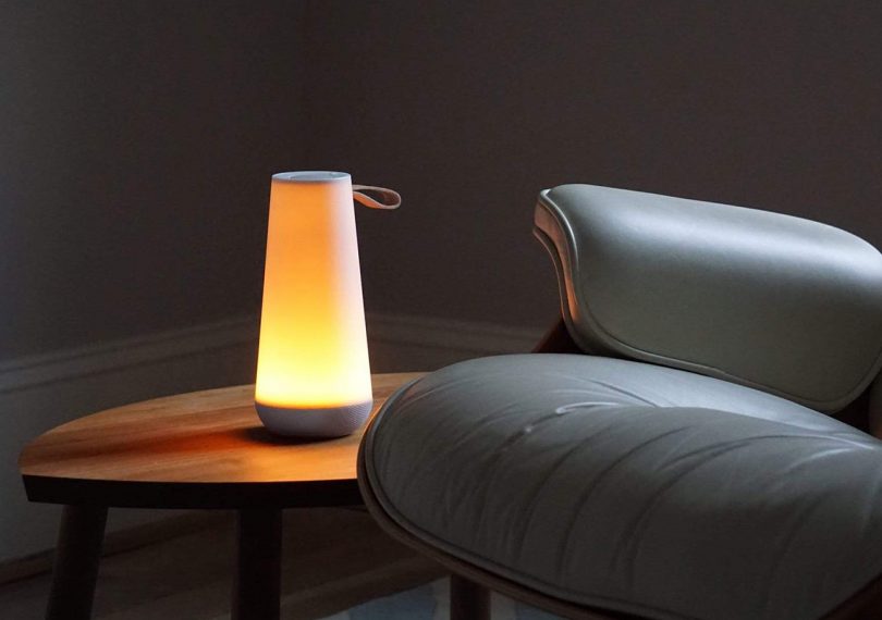 Pablo Designs UMA Mini Light and Speaker on a side table illuminating a dark room