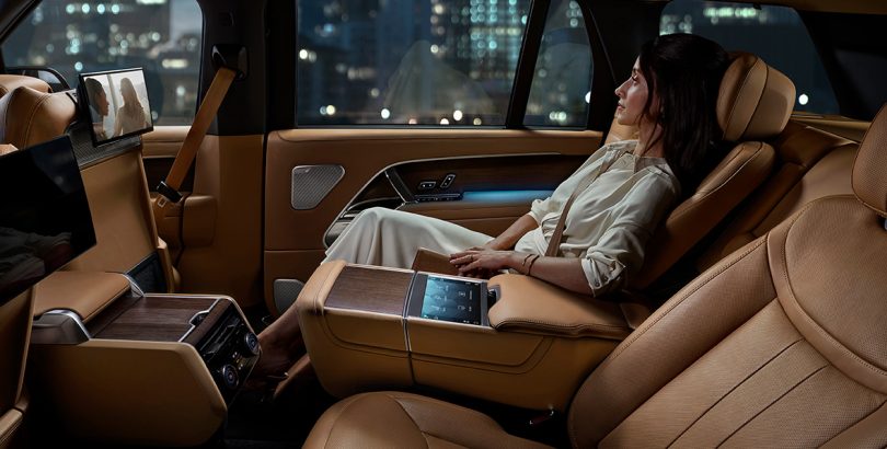 Woman reclined in rear seat of Range Rover watching entertainment screen.