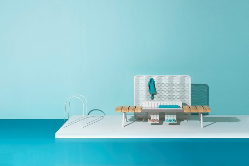 wood and aluminum outdoor bench and table on blue floor in front of light blue wall