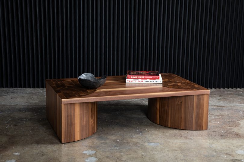rectangular coffee table styled with books on cement floor with black background