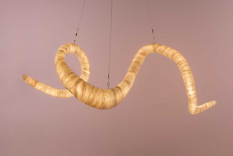 lit winding sculptural hanging light fixture suspended from ceiling