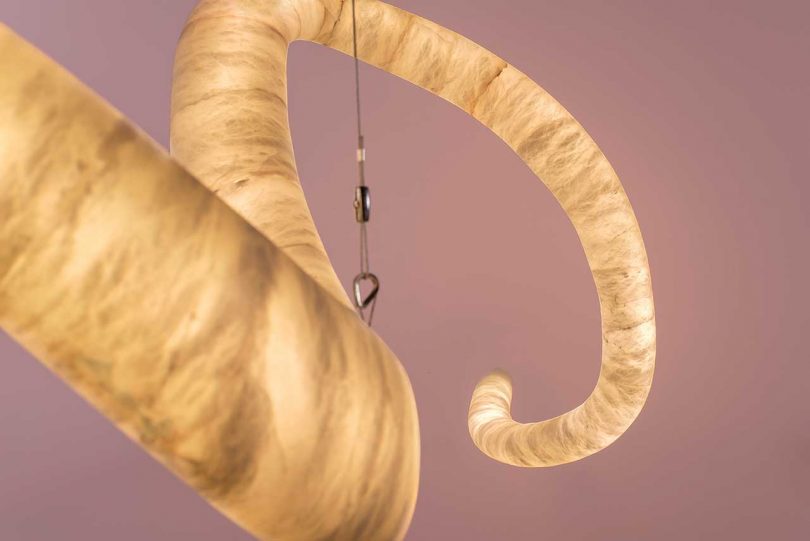 lit winding sculptural hanging light fixture suspended from ceiling