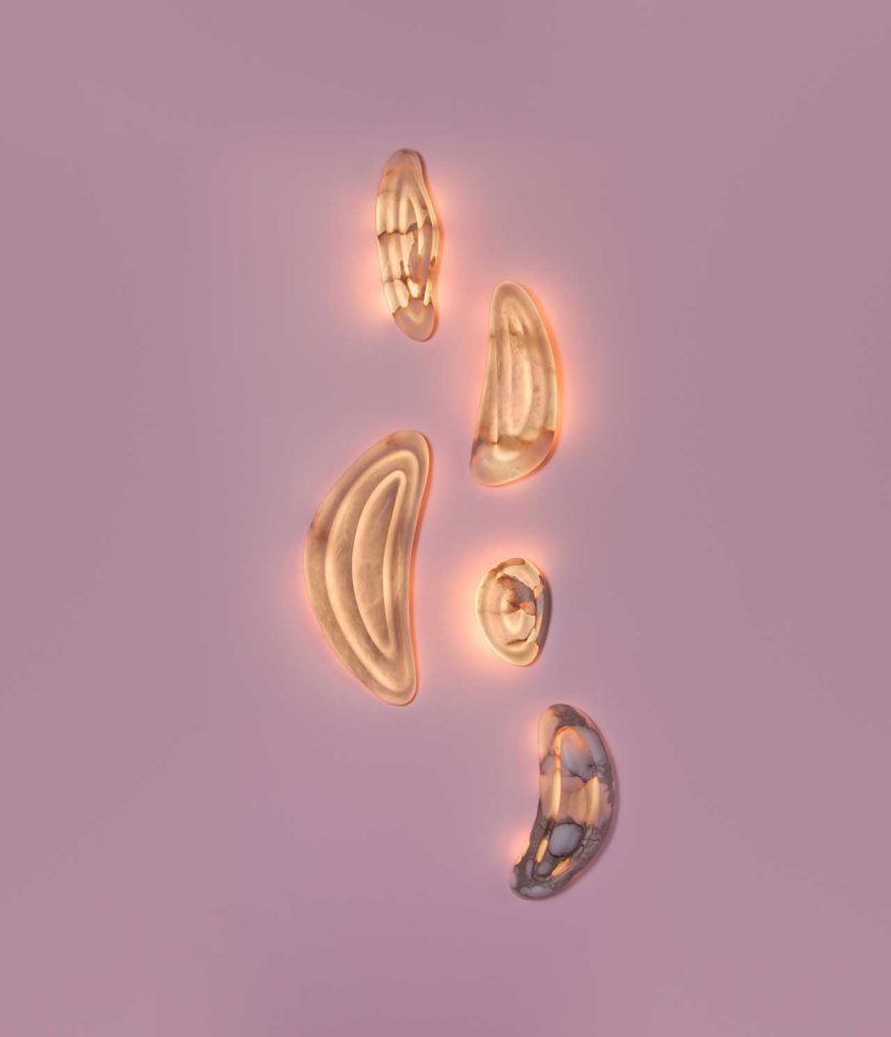 five lit abstract wall lights hanging on pink wall