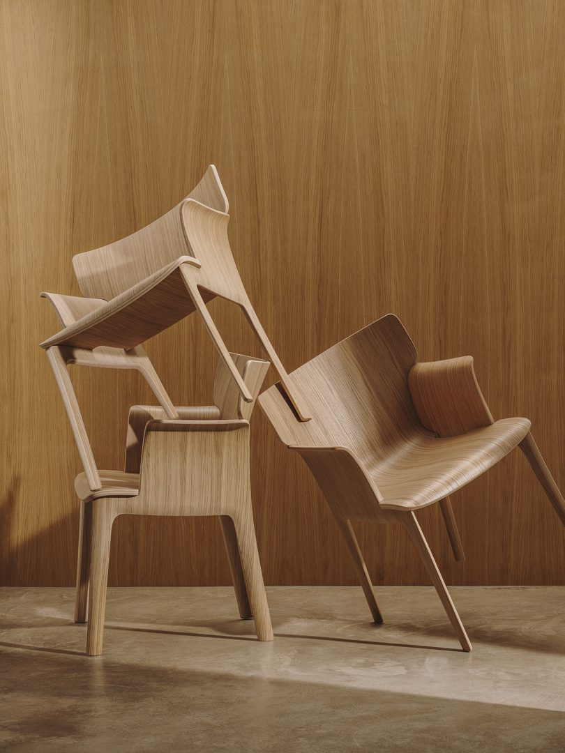 three wood armchairs balanced on top of one another in front of wood paneled wall