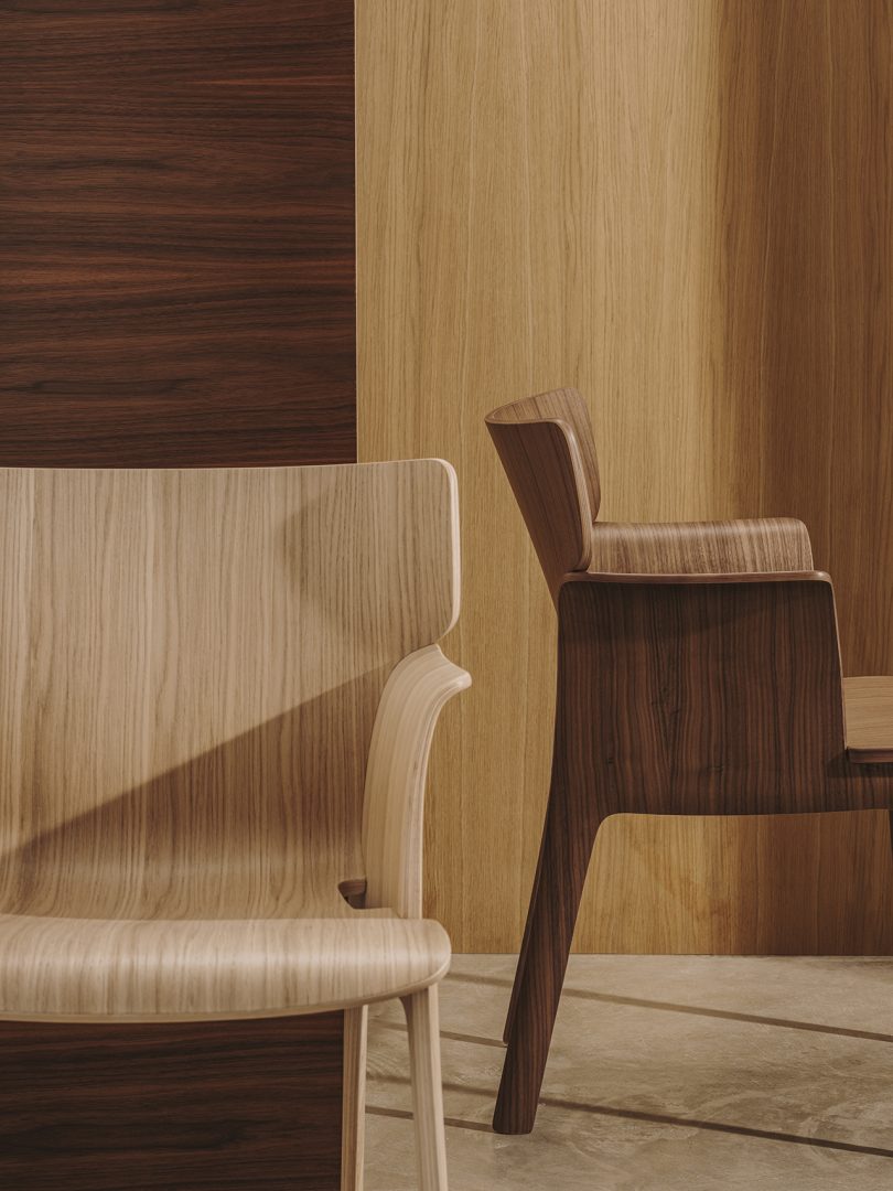 two wood armchairs in front of wood paneled wall