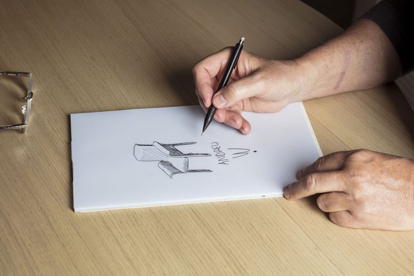 hand sketching an armchair on white paper