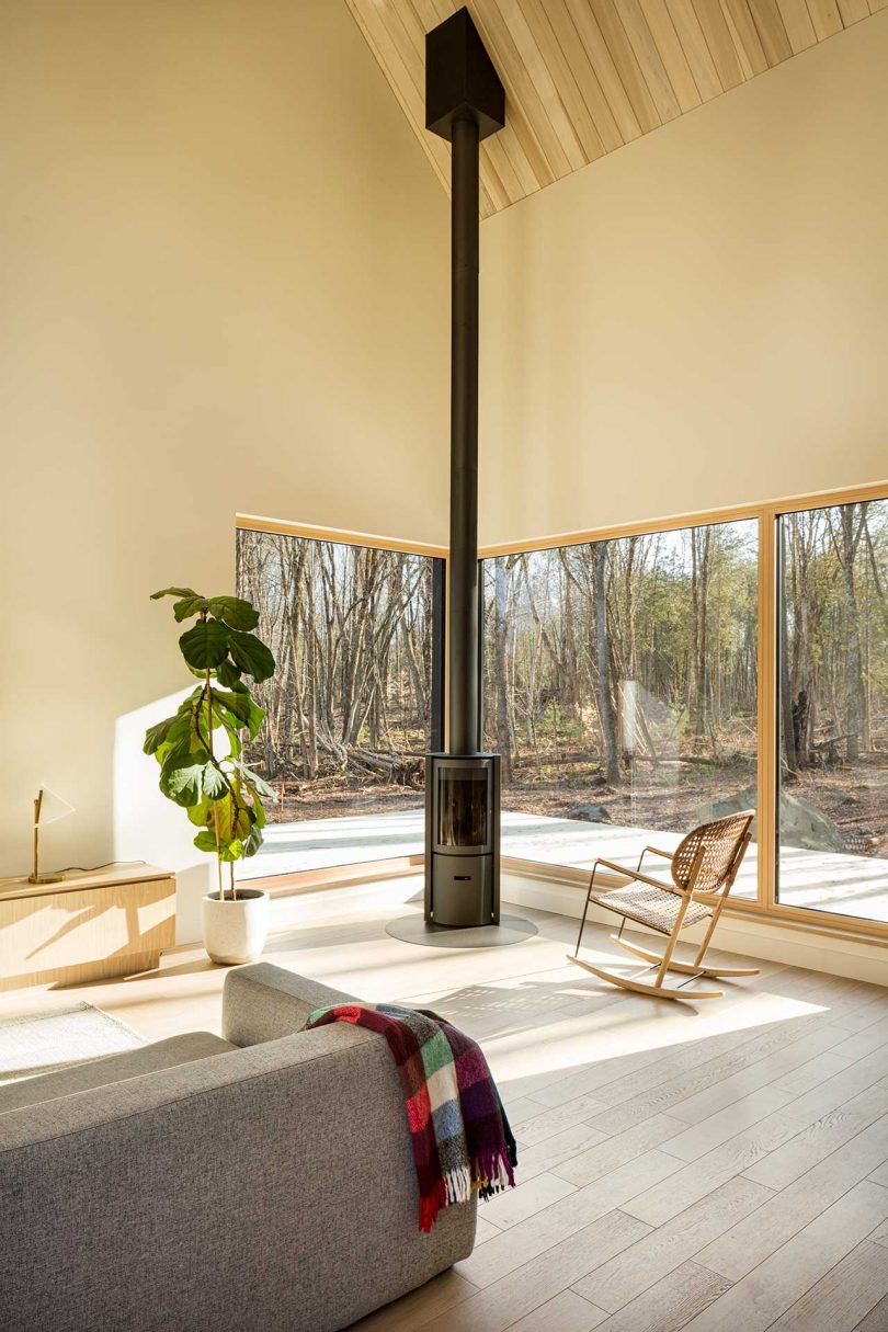 corner of modern living room in cabin with windows looking out to forest