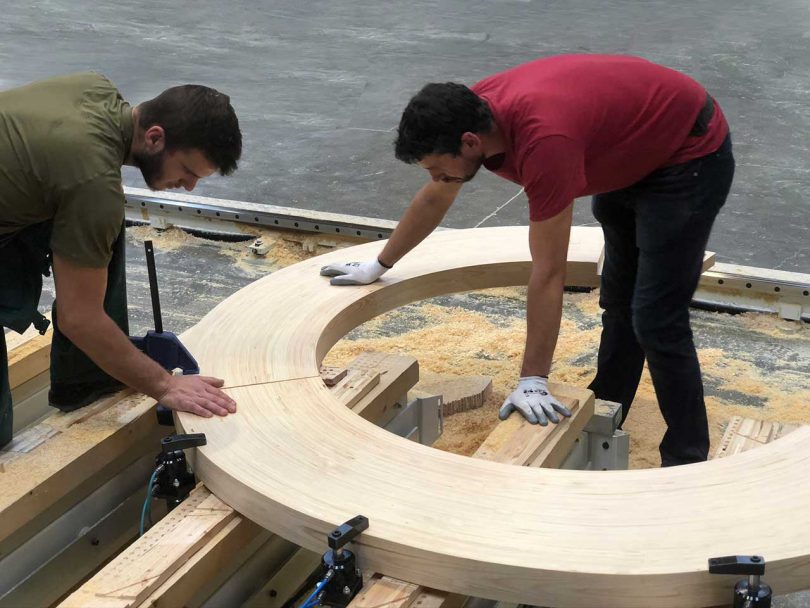 two men working on a circular wood design in shop