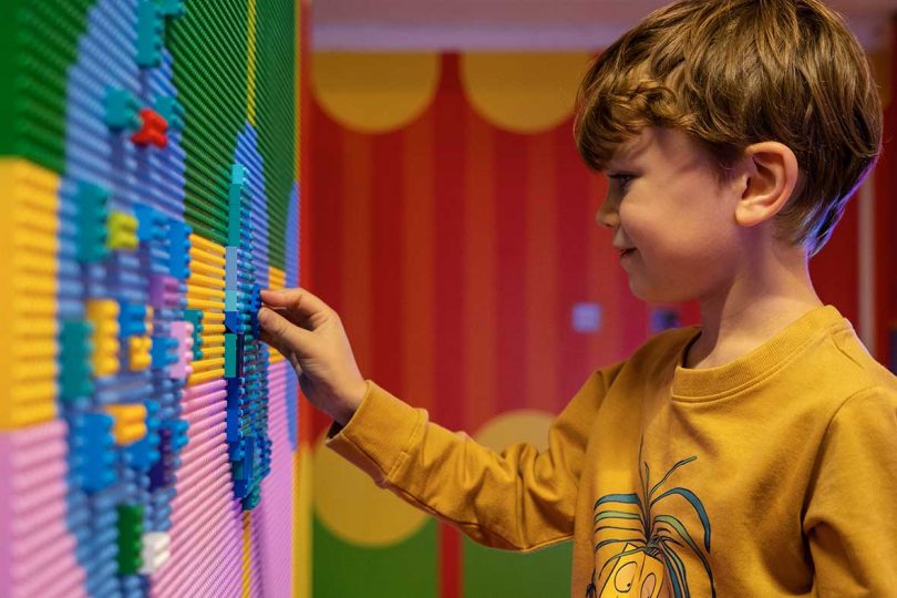 young boy playing with LEGO bricks on wall