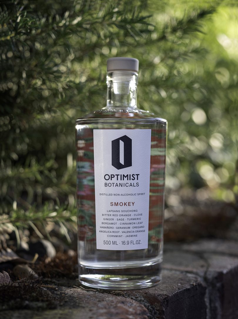 Optimist bottle in front of greenery outdoors