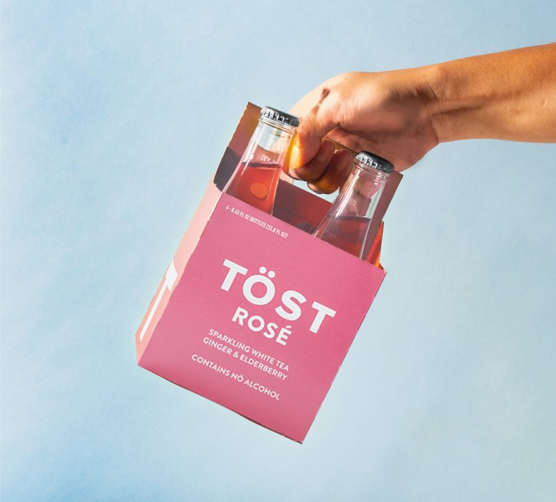 hand holding 4-pack of TOST alcohol free Rose