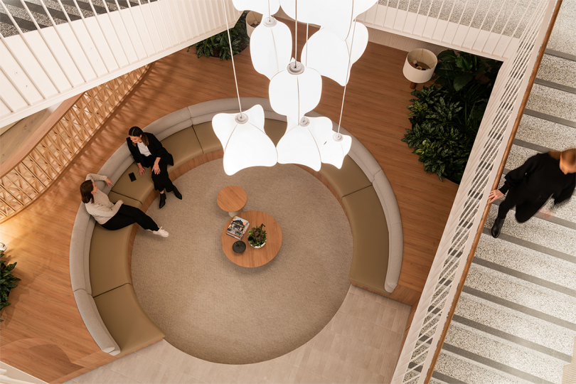 overhead image of lobby space with sculptural light fixture and circular seating with two people seated