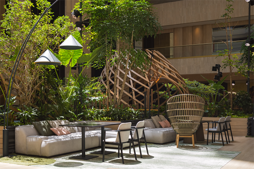 open interior space with nest-like sculpture, tables and chairs, and lots of greenery