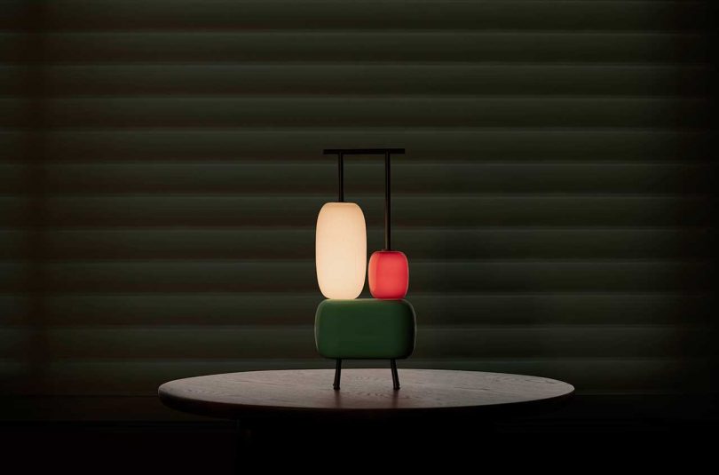 sculptural colorful lamp turned on against a dark background