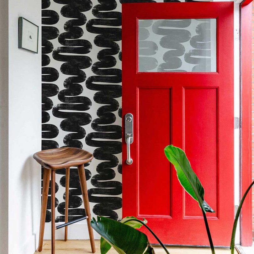 bold black & white squiggle wallpaper in front entryway with red door
