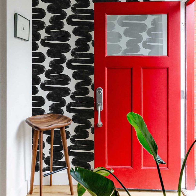 modern entrance with red door and black scribble wallpaper and wooden stool