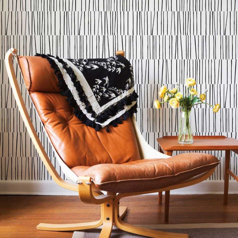 mini striped black and white wallpaper with brown leather lounge chair and table
