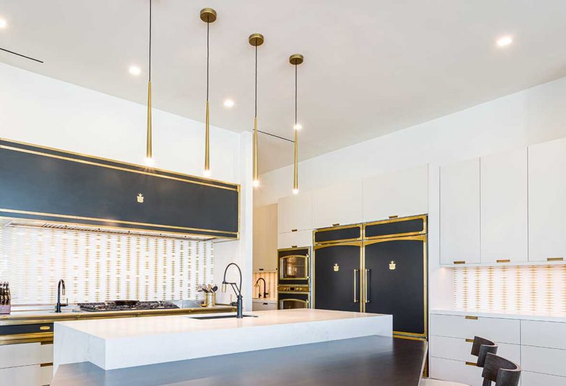 modern kitchen with white cabinets, brass accents and dark blue details