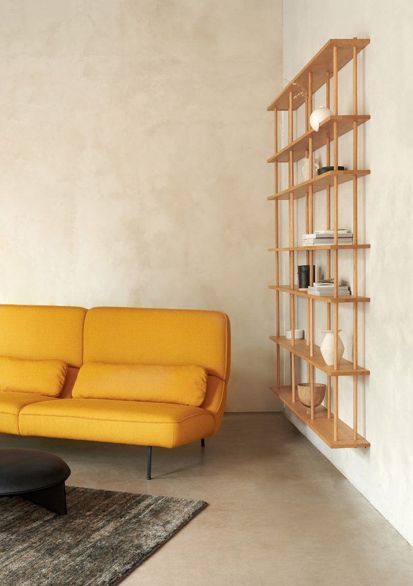 goldenrod sofa in corner of room next to large wall shelf