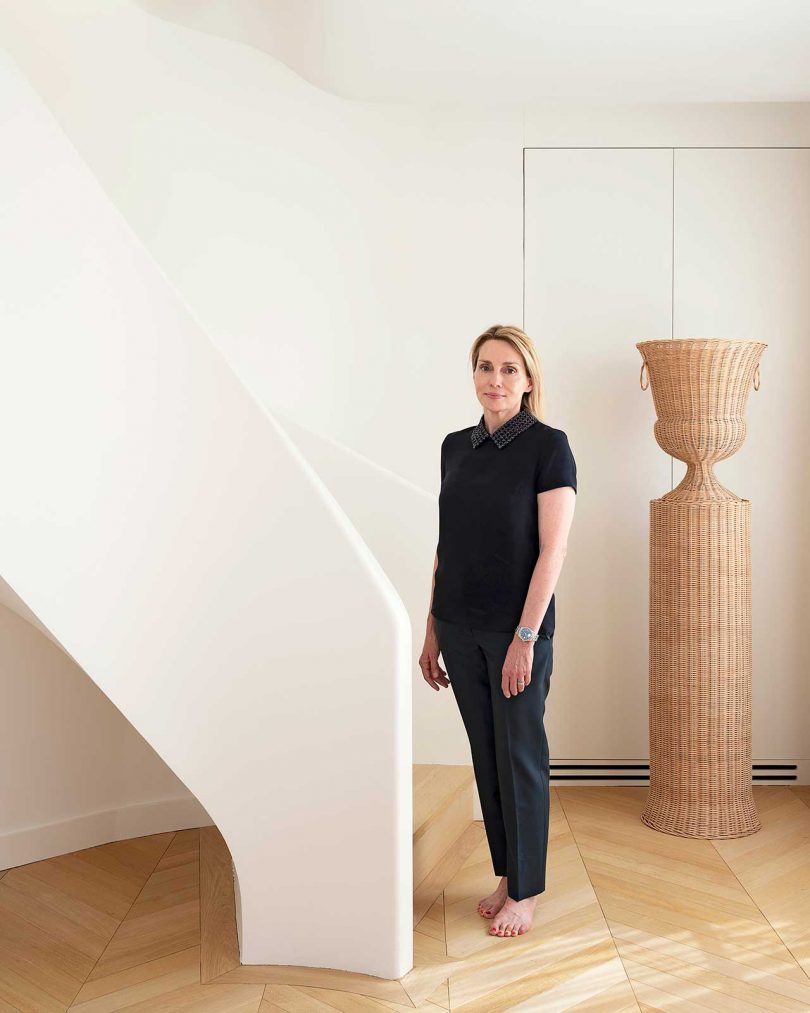 designer Isabelle Dubern-Mallevays standing in white space with curved stairs