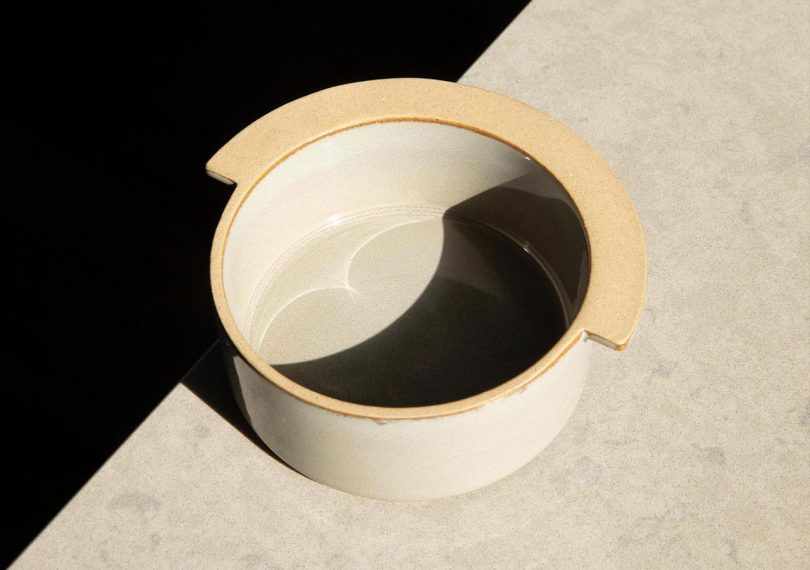 departo little ceramic bowl on tabletop with intense shadow cutting across it