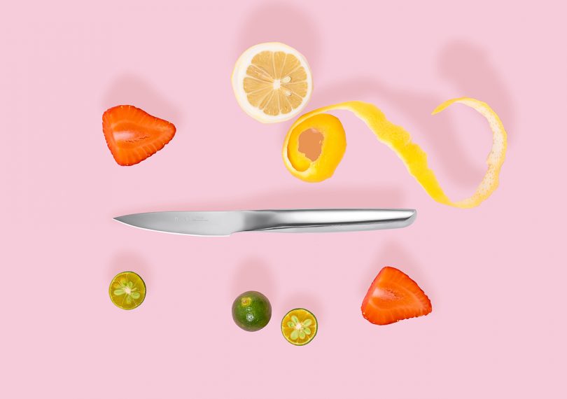 Hast Glossy Paring Knife with sliced fruit ingredients and citrus peel on a pink background