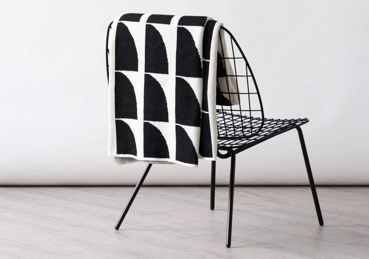 Jaws Black and White Throw by Happy Habitat slung over a chair