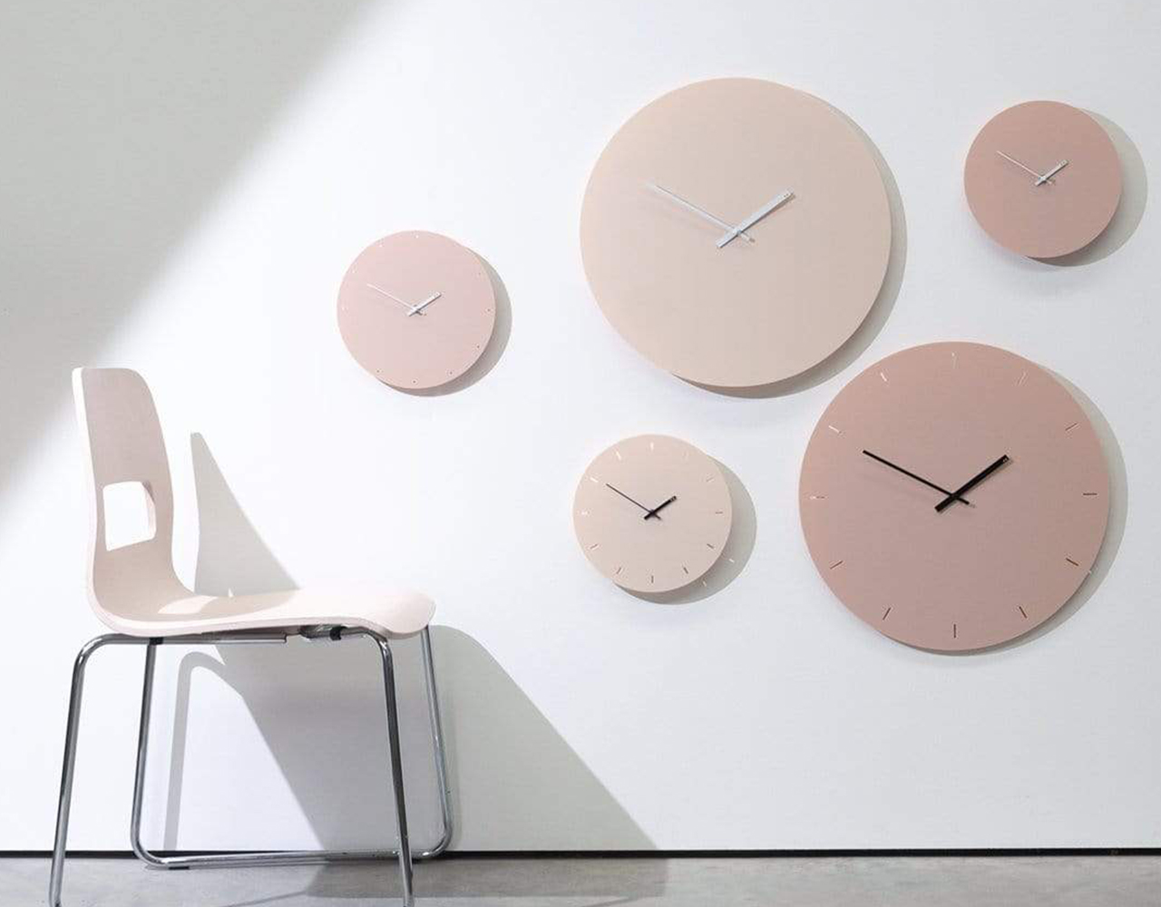 TOO Designs minimal wall clocks in almond cream with a chair in front of the wall