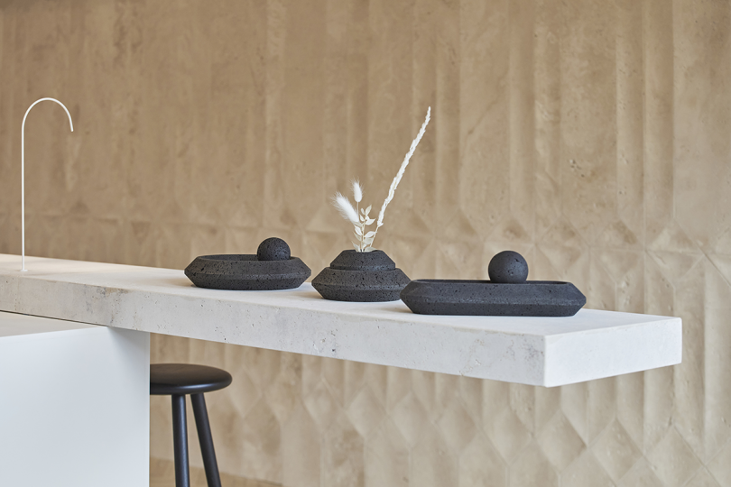 three black vessels on a long counter