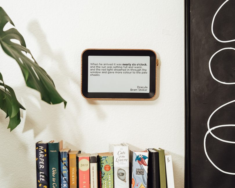 digital screen device hanging on white wall above books