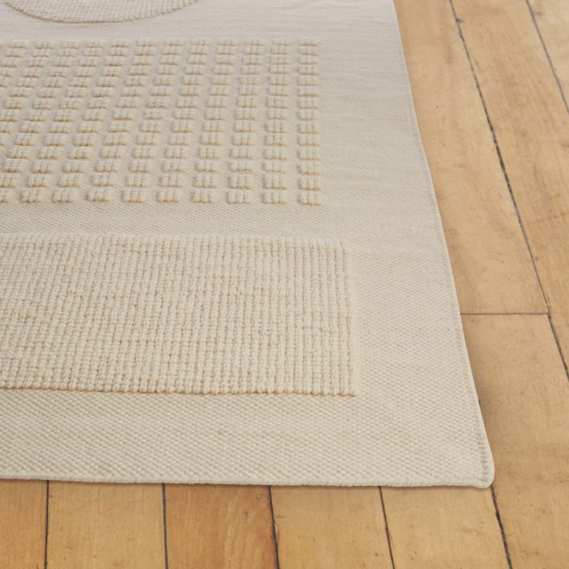 corner of cream rug on wood floor