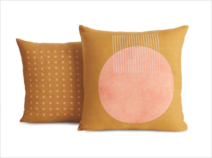 two goldenrod and pink patterned pillows on white background