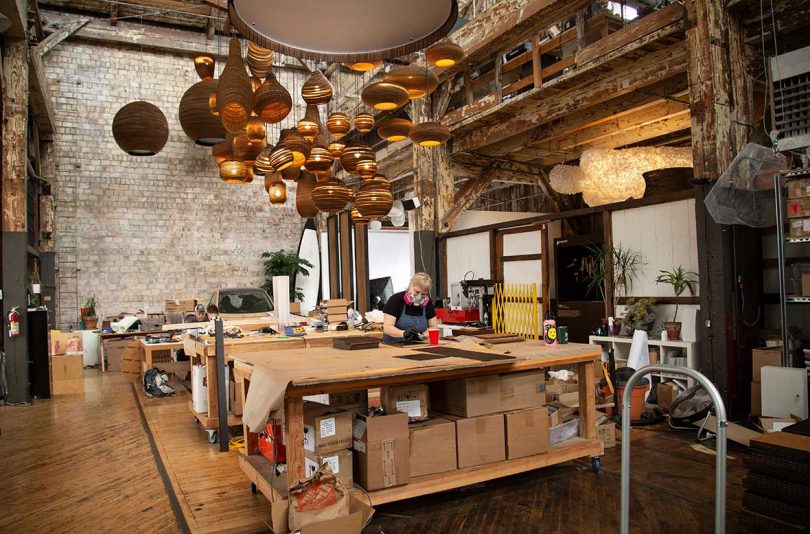 open workshop with work tables and hanging round cardboard light fixtures