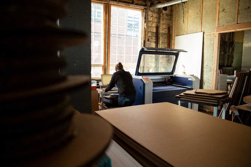 person using a laser cutter by window of workshop